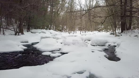 Low flying drone above a snowy river in winter