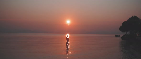 Silhouette of a young woman stretching her arms in front of the sunrise