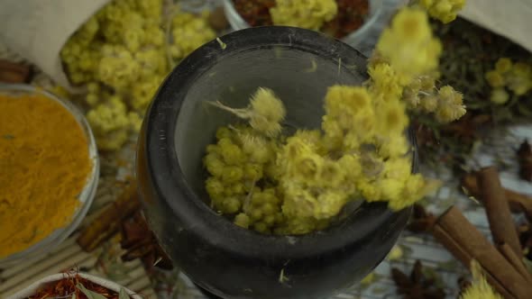 Flowers and herbs falling into the granite mortar