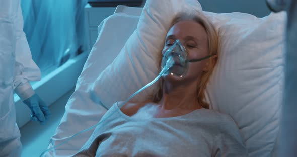 Covid 19 Infected Patient with Oxygen Mask Lying on Bed in Quarantine Room