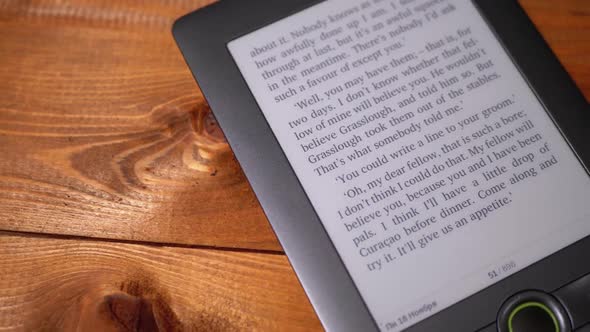 The Electronic Book Lies on a Wooden Table. Screen of Electronic Ink Displays Text of the Book