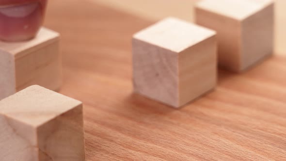 Hand lines up wooden cubes of educational game with wood blocks