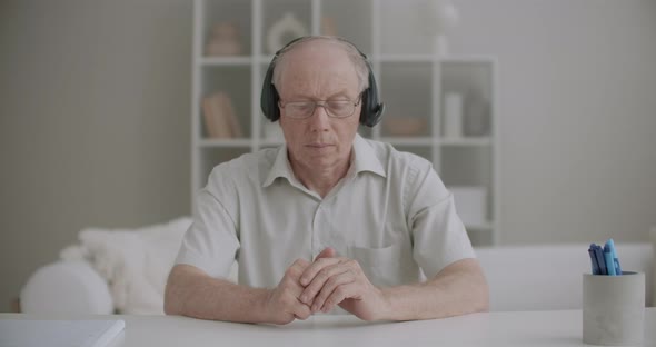 Aged Man Is Listening Online Lecture Through Headphones, Nodding Head Agreement, Medium Portrait at