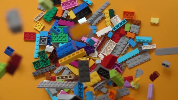 Falling colorful plastic toy bricks in box. Slow motion 240 fps, Top down view