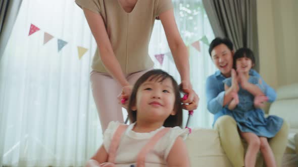 Attractive happy family, mother play with young child daughter in living room with father in house.