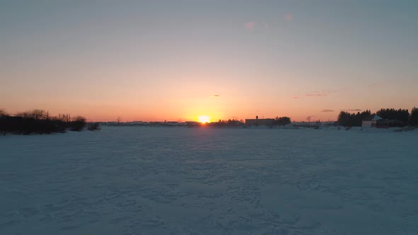 Aerial Over the Frozen River Surrounded with Forest at Sunset Siberia