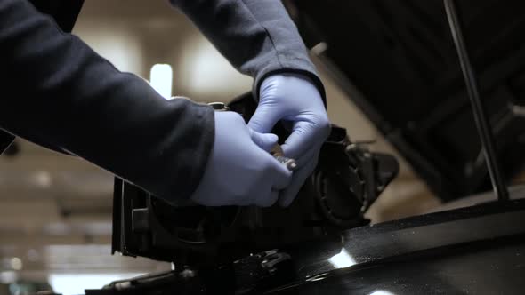 A mechanic changing a broken halogen lamp from a car's headlight. Professional expertise in action.