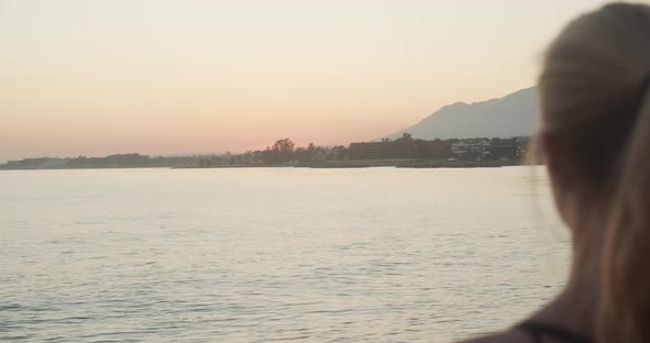 Woman Watching Sunset Over Sea And Coastline