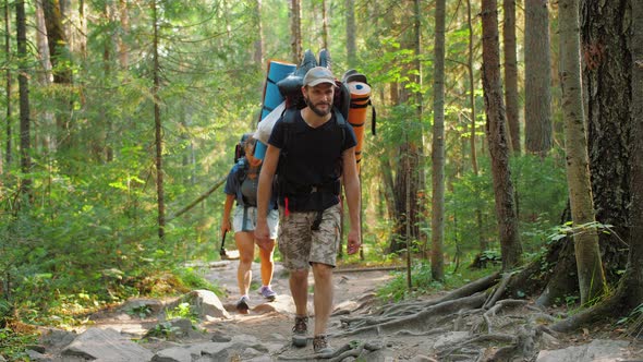 Group of Tourists with Backpacks and Equipment Walking Forest Trail