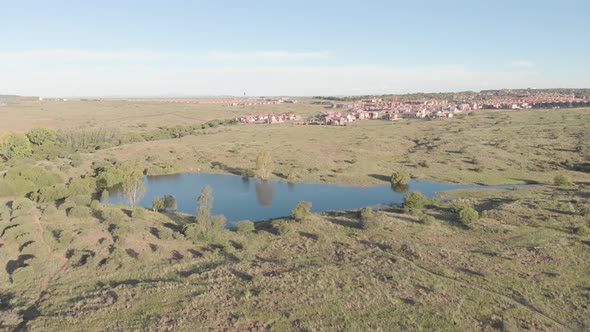 AERIAL Reverse Shot of a DAM in a Green Valley with Housing in the BACK