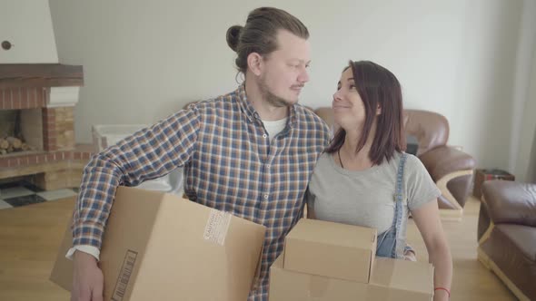 Portrait of Caucasian Couple Standing with Cardboard Boxes in Living Room and Smiling