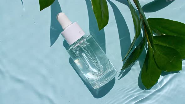 Glass Cosmetic Bottle with Pipette Lies on the Surface of the Water