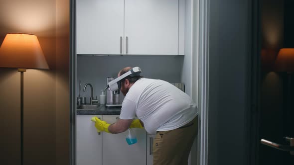 Overweight Man in Vr Headset Clean Kitchen at Home Using Detergent Spray and Cloth