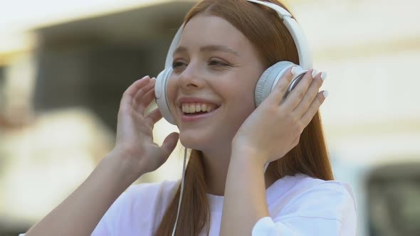 Cheerful Young Woman Listening to Music by Headphones Smiling on Camera, Fun