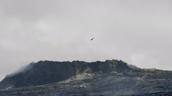 Helicopter Flying Above Smoking Lava Field