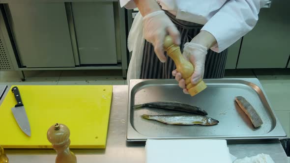 Chef Peppering and Salting Fish on a Tray