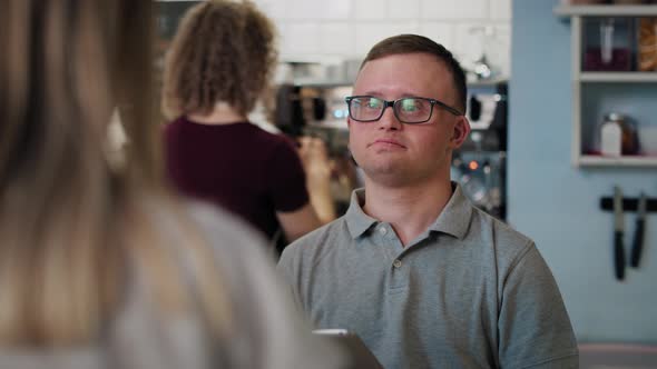 Caucasian man with down syndrome taking order in the cafe using a digital tablet. Shot with RED heli