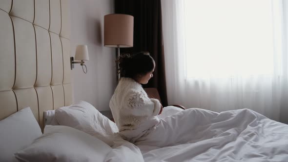 A Pretty Young Smiling Woman Wakes Up in the Morning Stretches Out in Bed and Looks Pleased