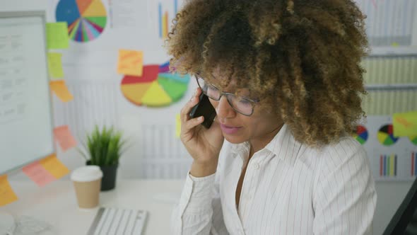 Thoughtful Woman in Office Talking on Phone