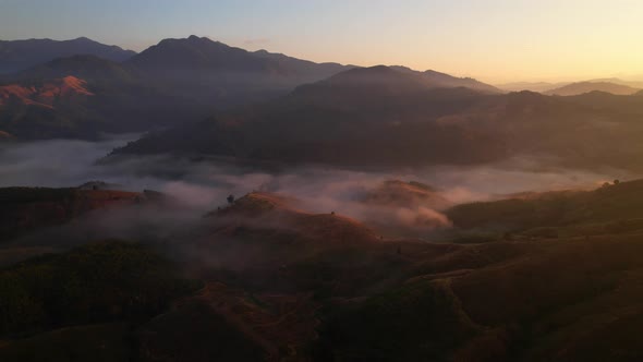 4K aerial view over a misty mountainous area. The great golden sun in the morning