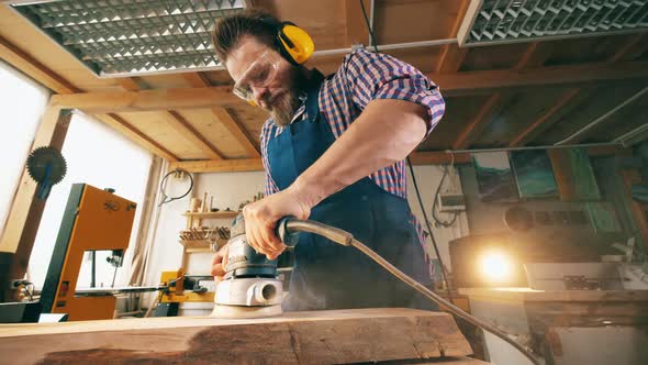 Carpentry with a Male Worker Polishing Wood Mechanically. Craftsman Working in Carpentry