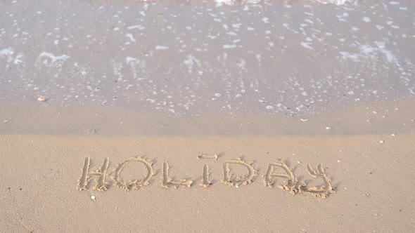 Holiday Lettering Holiday Lettering on Sand Among Waves Crashing on Beach