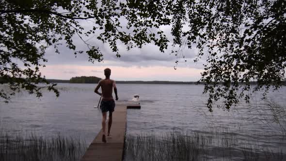 Young adults go swimming off the end of a lake dock.