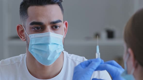 Closeup Arabic Spaniard Man in Medical Mask Sits in Clinic Hospital Preparing for Vaccination