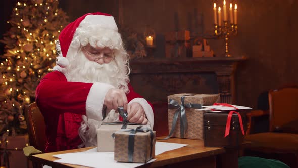 Workplace of Santa Claus. Cheerful Santa is working while sitting at the table.