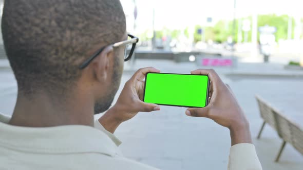 African Man Watching Smartphone with Green Screen Outdoor