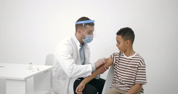 Male Pediatrician Giving a Vaccine Shot to a Black Kid