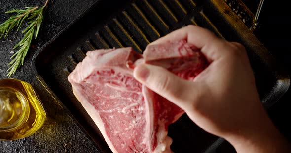 The Men's Hand Puts the Steak T-bone Raw Beef in the Pan. 
