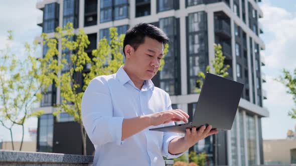 Handsome Chinese Businessman Holding Laptop Writing Emails Working Outdoor