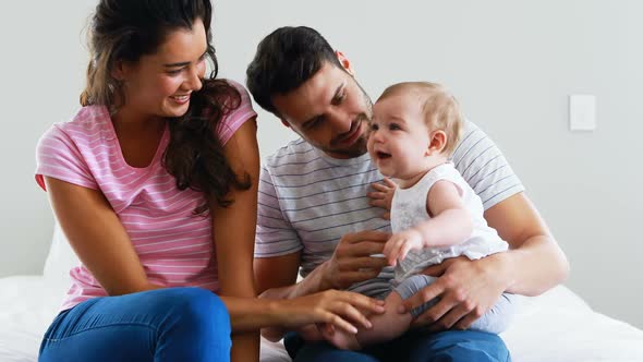 Parents playing with their baby girl in bedroom