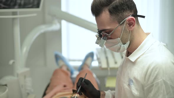 Dentist at work. Young man in special magnifying glasses and medical clothes