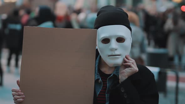 Young Woman Removing Theater Mask While Holding Black Cardboard in the Crowd. Protest Against