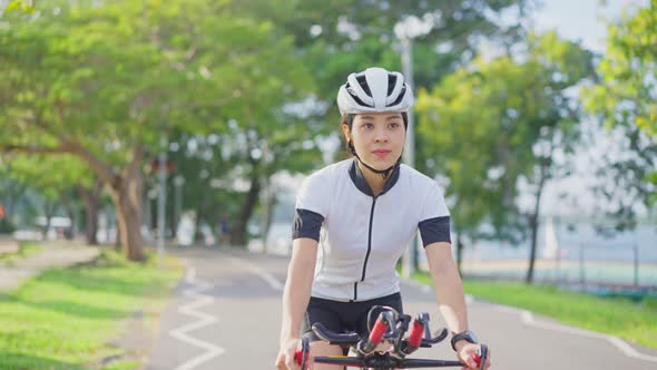 Asian young beautiful woman in sportswear riding bicycle for health in the evening in public park.