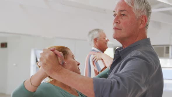 Caucasian senior couples spending time together in a ballroom taking part in dancing class