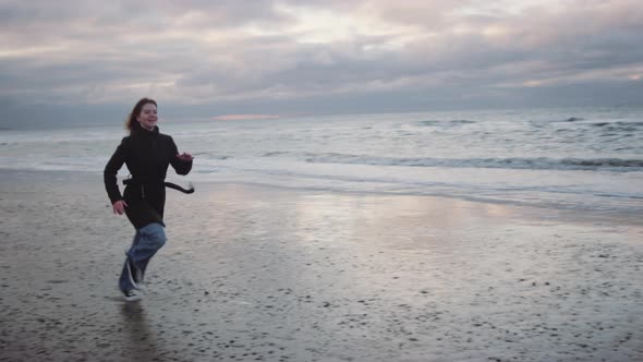 Redhead In Black Running Along Beach