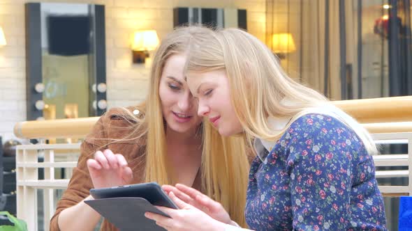 Two Blondes Sitting on a Bench Talking, Bragging About Their Purchases. CLose Up