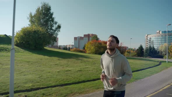 Man Running on Jogging Track at the City Park in Sunny Autumn Morning Side View