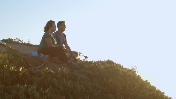 Couple of Hikers Sitting at Cliff on Slope