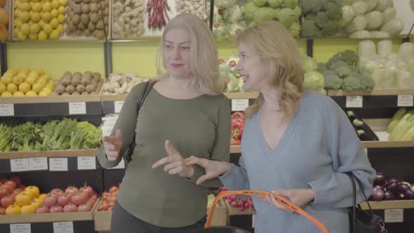 Positive Caucasian Adult Women Talking and Laughing in Grocery Store. Blond Housewives Chatting As