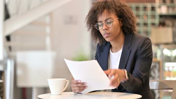 Professional African Businesswoman Reading Documents in Cafe