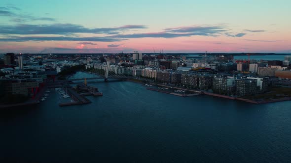 Aerial view around the Cruselli bridge, colorful dusk in Ruoholahti, Helsinki, Finland - circling, d