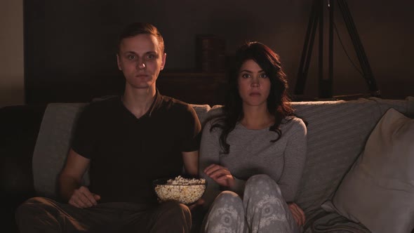 Young Couple Watching Something on Tv at Home and Eating Popcorn