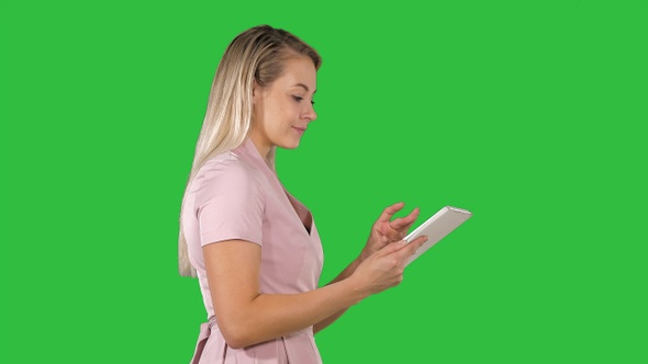 Beautiful woman uses a tablet and walks on a Green Screen