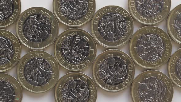 British One Pound Coins Engraved With Iconic Floral Design Flat Lay On White Table - Closeup Slider