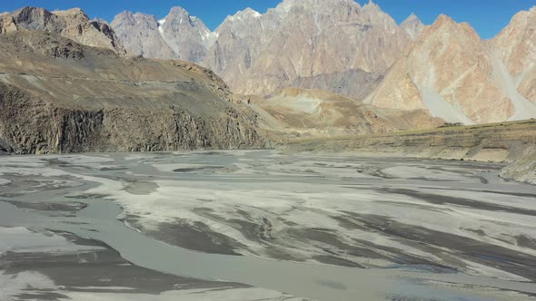 slowing aerial drone panning up from the river and revealing Passu Cones mountains in Hunza Pakistan