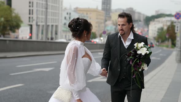 Just Married Couple is Walking on City Street in Wedding Day Bride and Groom